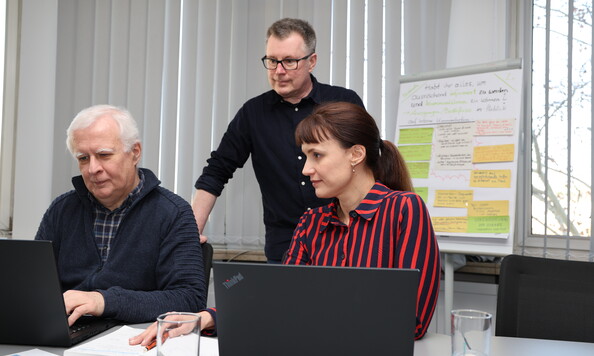 Drei Kollge:innen in einer Besprechung